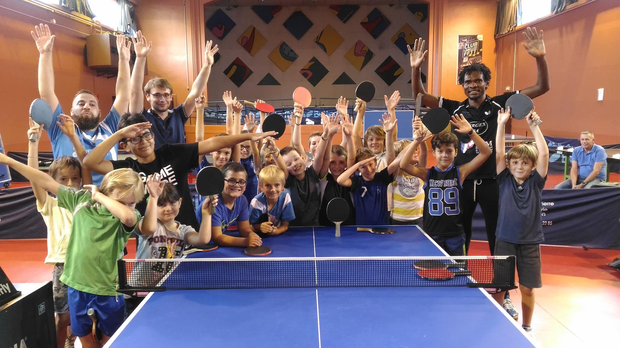 Jeunes de l'académie d'Annecy Tennis de Table avec leurs entraîneurs, raquettes levées